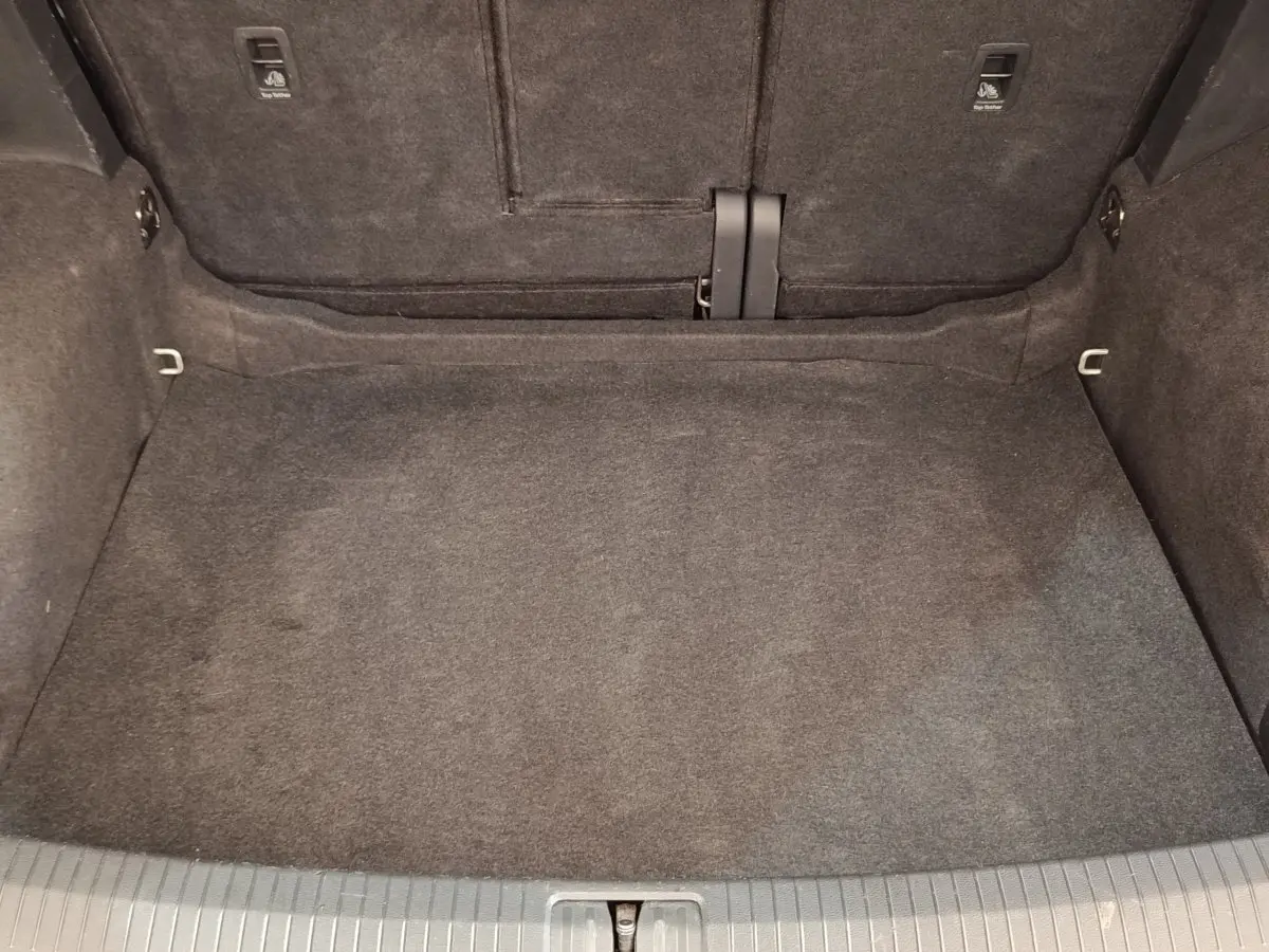 Coffre vide du Volkswagen Tiguan 2.0 TDI 150 DSG7 Elegance, vue intérieure arrière avec moquette grise.