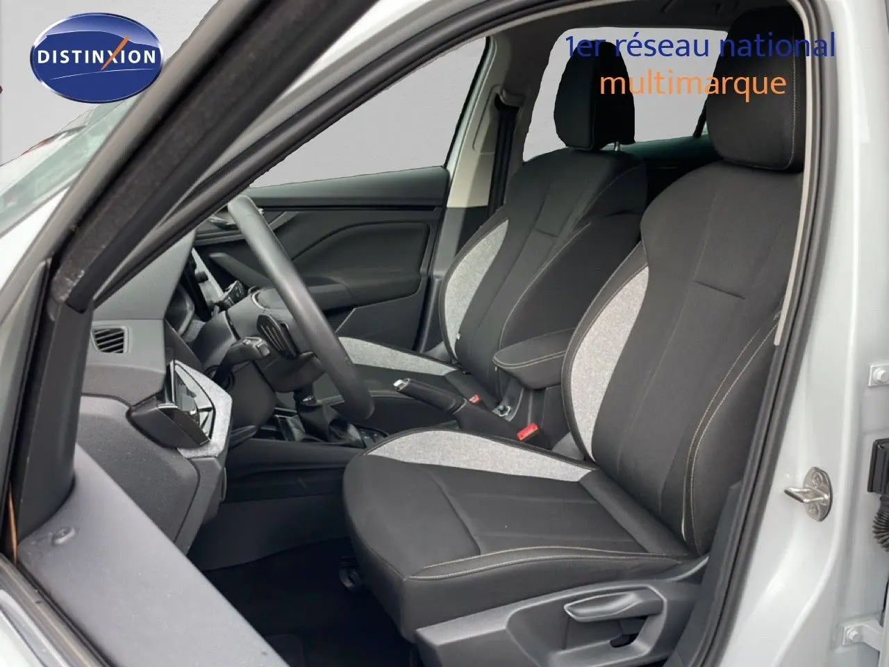 Vue intérieure côté gauche de la Skoda Kamiq 2025 blanc glacier, montrant les sièges avant en tissu bicolore gris et noir.