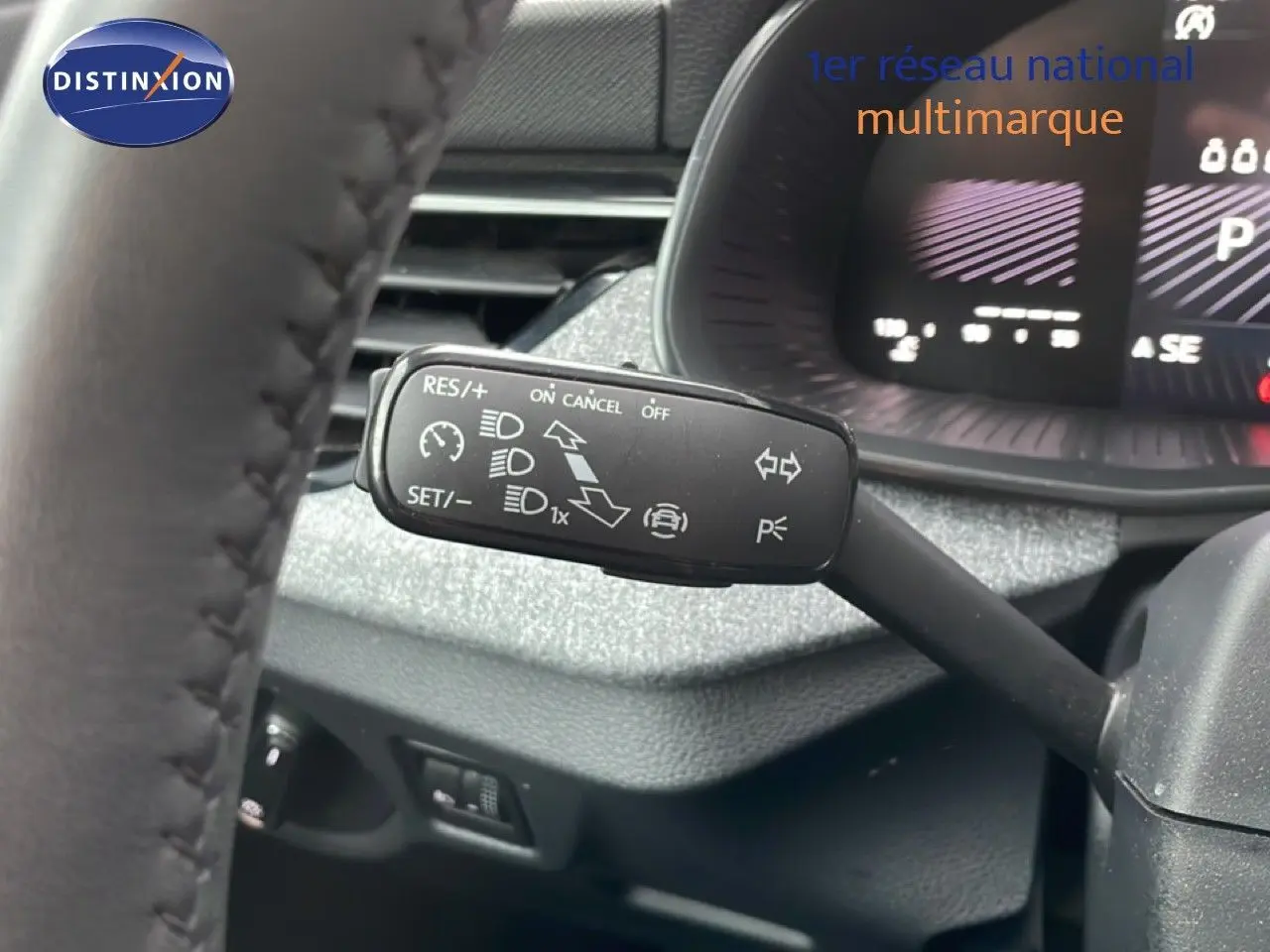 Gros plan sur le commodo gauche du volant d’un Skoda Kamiq 2025, avec tableau de bord numérique en arrière-plan.