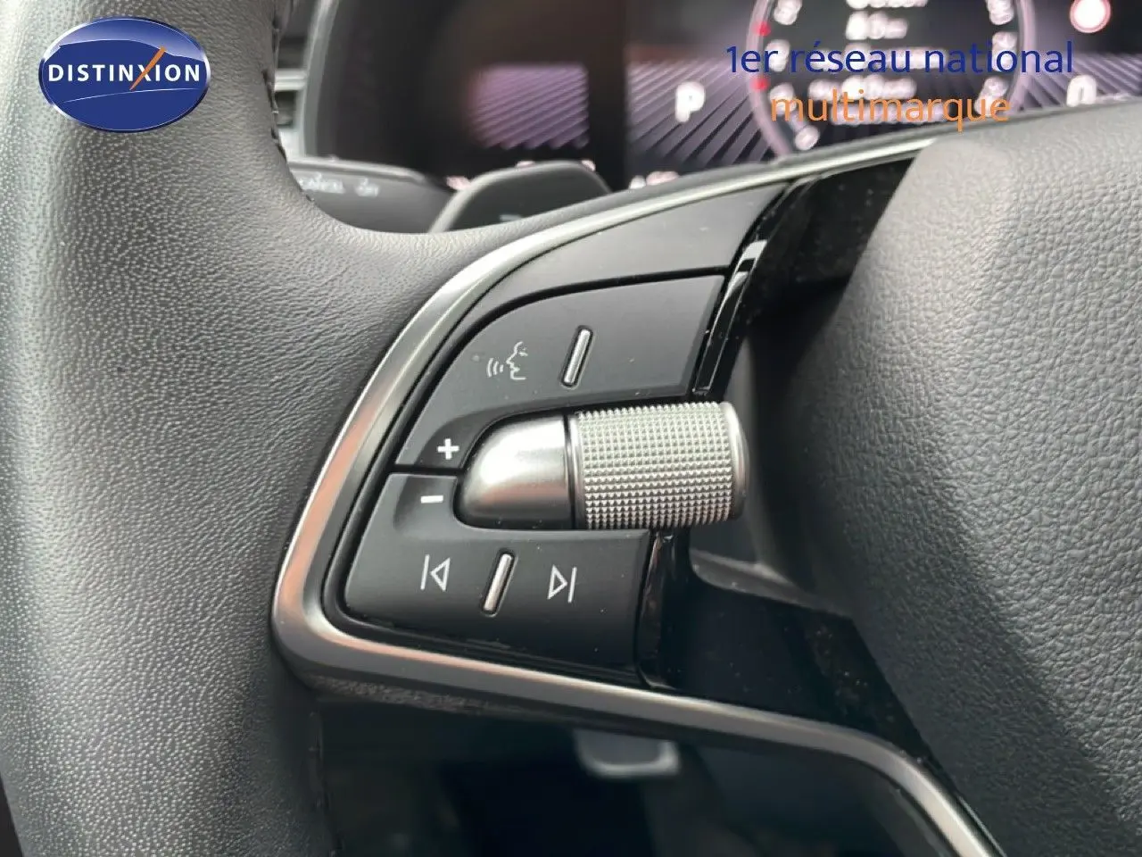 Gros plan sur les commandes gauche du volant noir du Skoda Kamiq blanc glacier, avec molette métallique et boutons multifonctions.