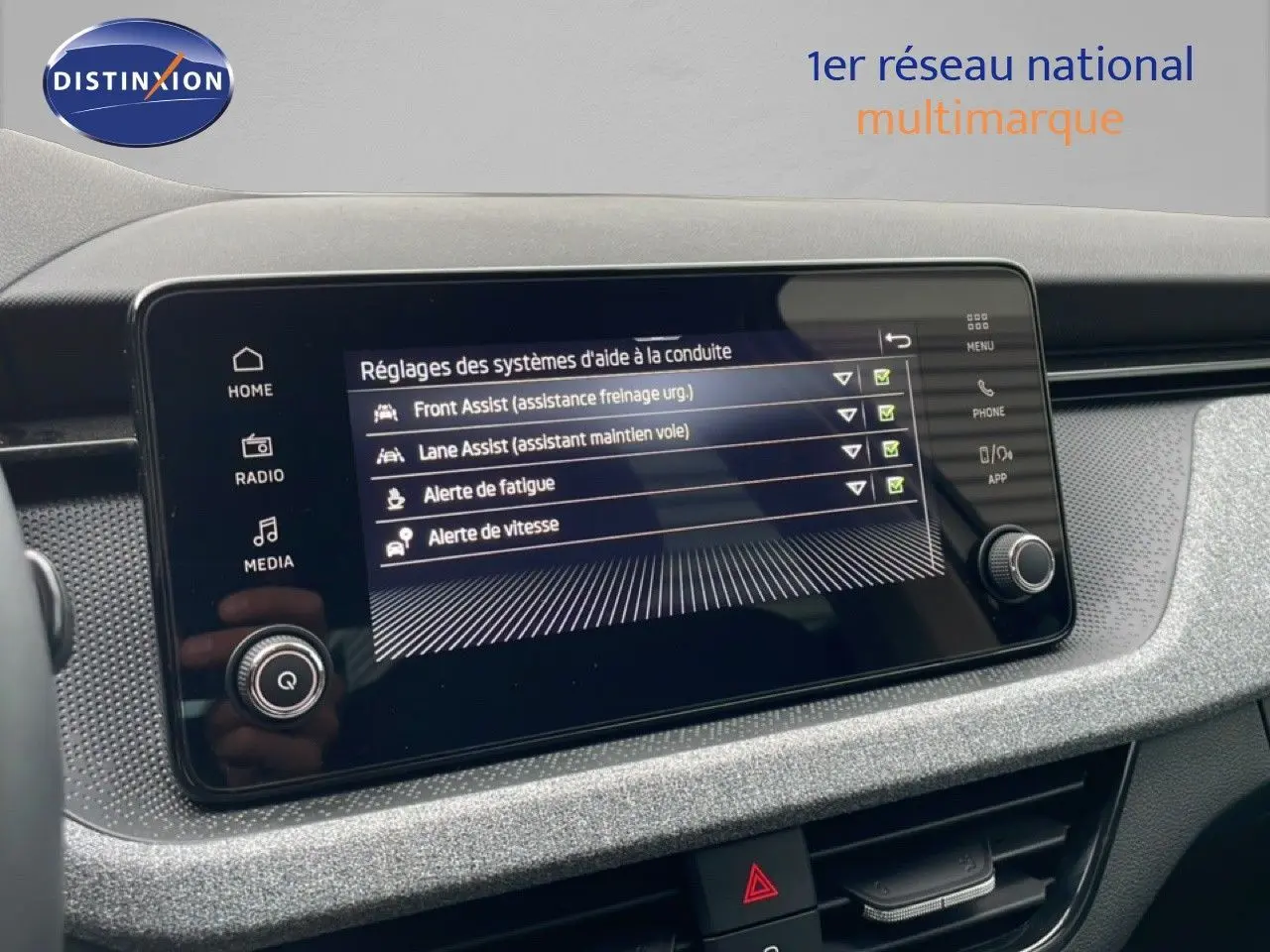 Écran tactile central du Skoda Kamiq 2025 affichant les réglages des aides à la conduite, tableau de bord gris texturé.