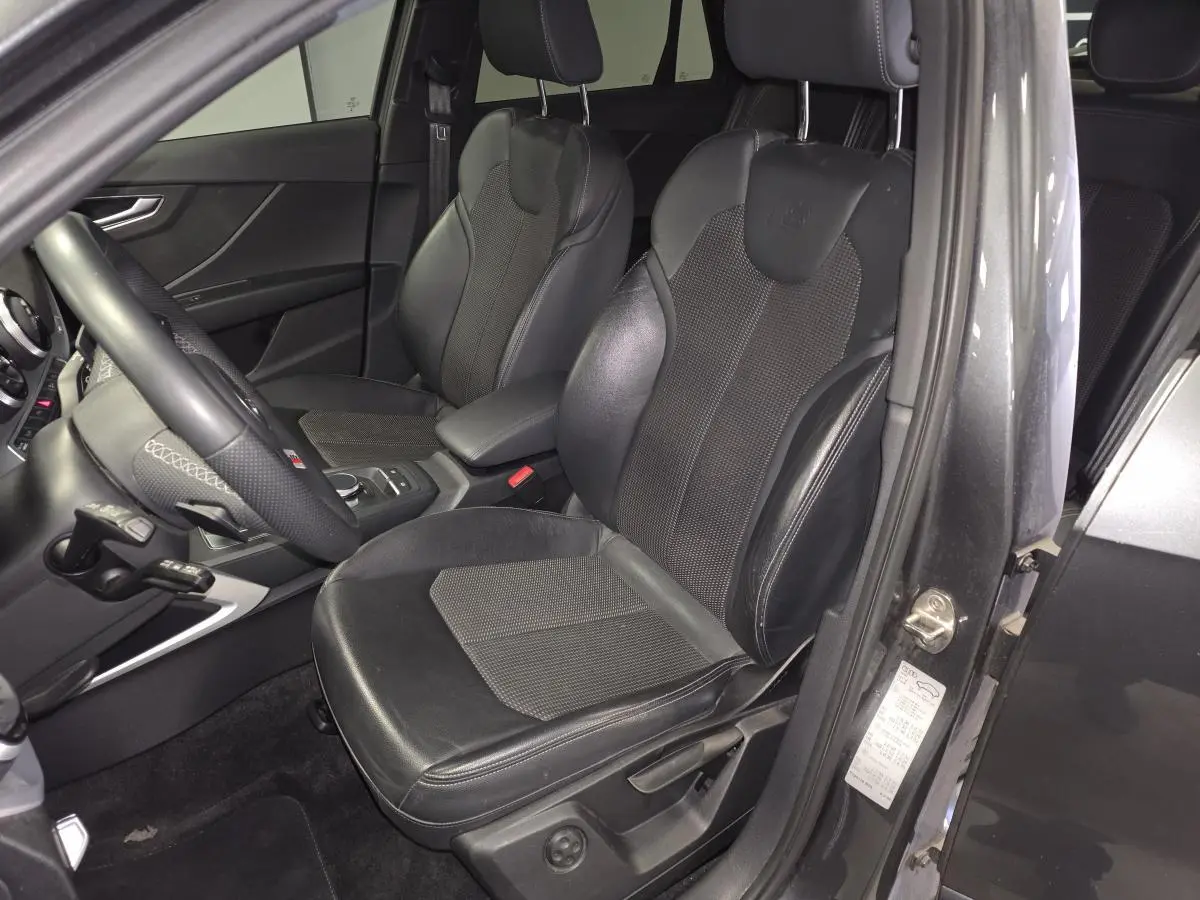 Vue intérieure côté conducteur de l'Audi Q2 gris avec sièges sport cuir/tissu et volant multifonction S line.