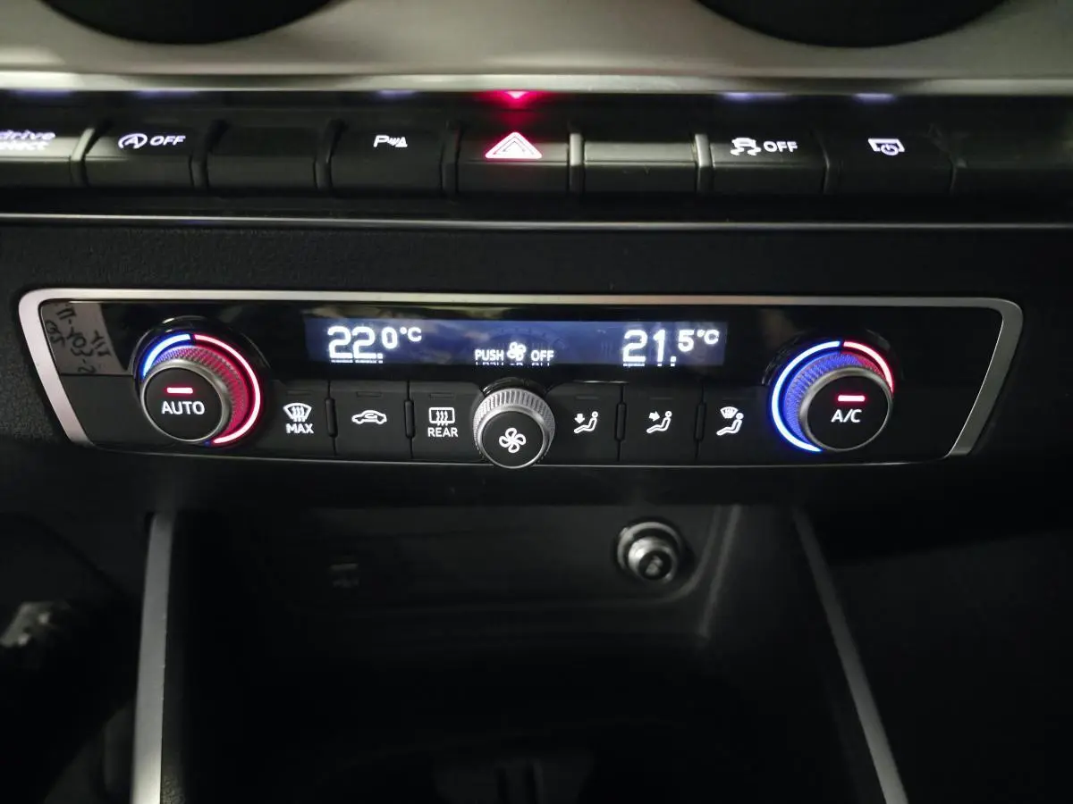 Détail du tableau de bord de l'Audi Q2 2023 avec commandes de climatisation automatique bicolores et affichage digital.