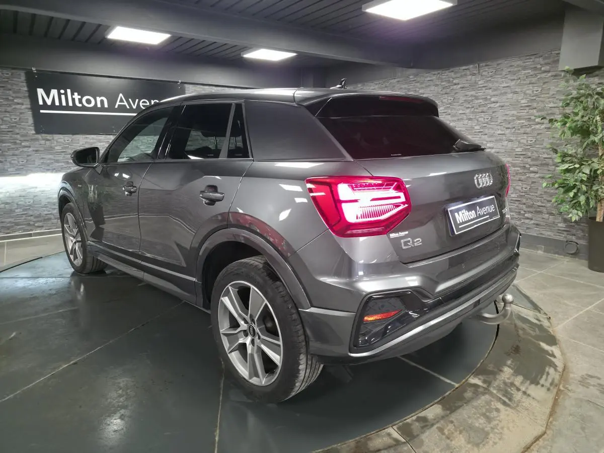 Vue 3/4 arrière droite d'un Audi Q2 gris Daytona avec attelage amovible et jantes 18 pouces en alliage.