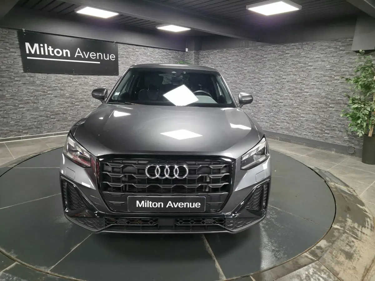Vue avant d’un Audi Q2 gris Daytona S line Plus 2023 avec calandre noire et logo Audi lumineux.