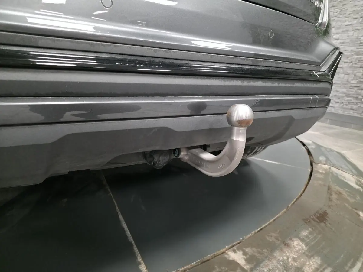 Gros plan sur l'attelage amovible sous le pare-chocs arrière gris nacré d'un Audi Q2 2023 S line Plus.