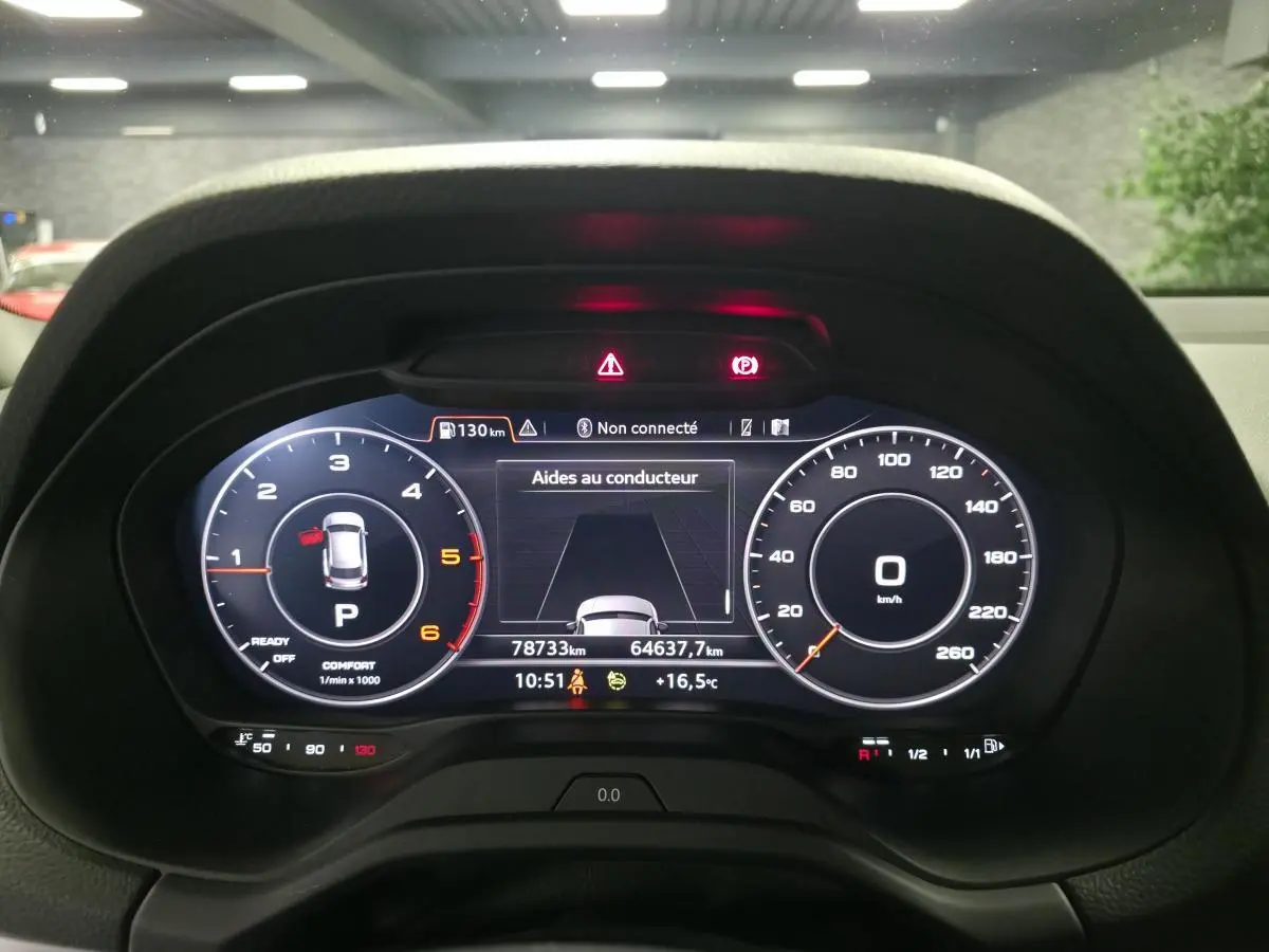 Vue rapprochée du tableau de bord numérique de l'Audi Q2 gris 2023, affichant les compteurs et aides au conducteur.