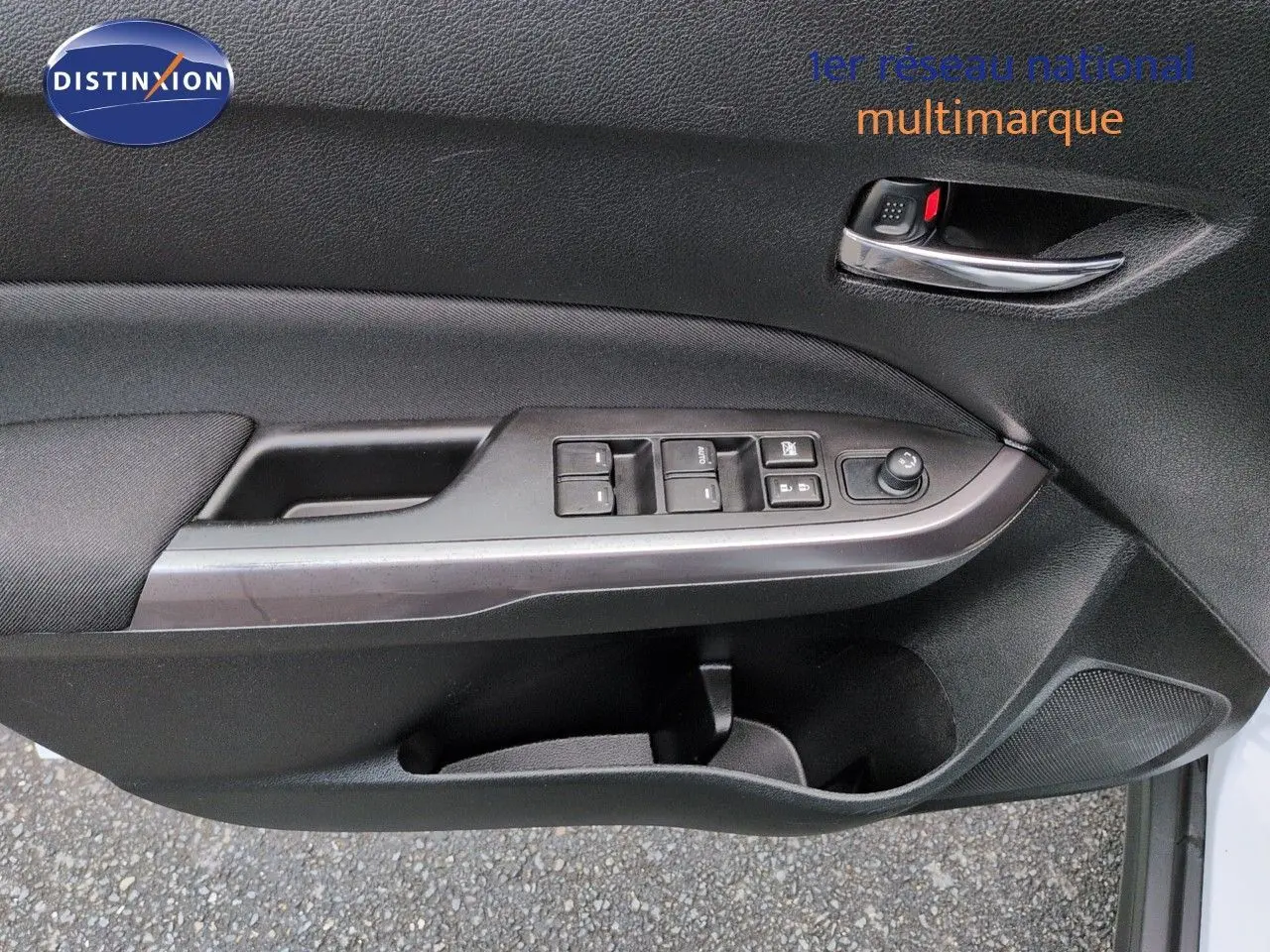 Gros plan sur la porte avant gauche du Suzuki Vitara 1.4 Boosterjet Hybrid, avec commandes électriques et poignée chrome.