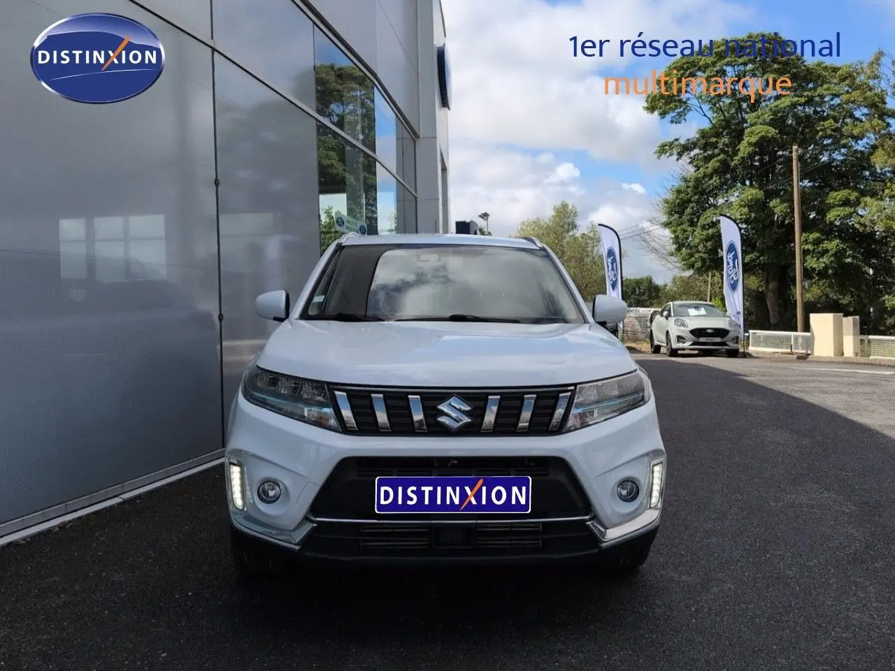 Vue frontale d'un Suzuki Vitara Galactic Gray métallisé avec calandre chromée et feux LED allumés.