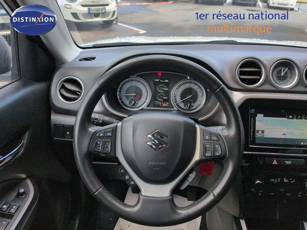 Vue intérieure centrée sur le volant cuir multifonction du Suzuki Vitara 2021 avec tableau de bord et écran tactile visible.
