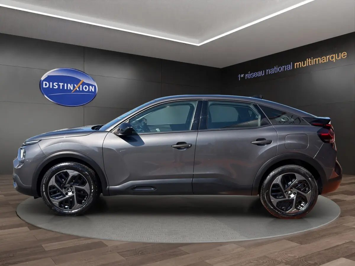 Profil droit d'une Citroën C4 gris foncé 2023 avec jantes noires et détails noirs contrastants.