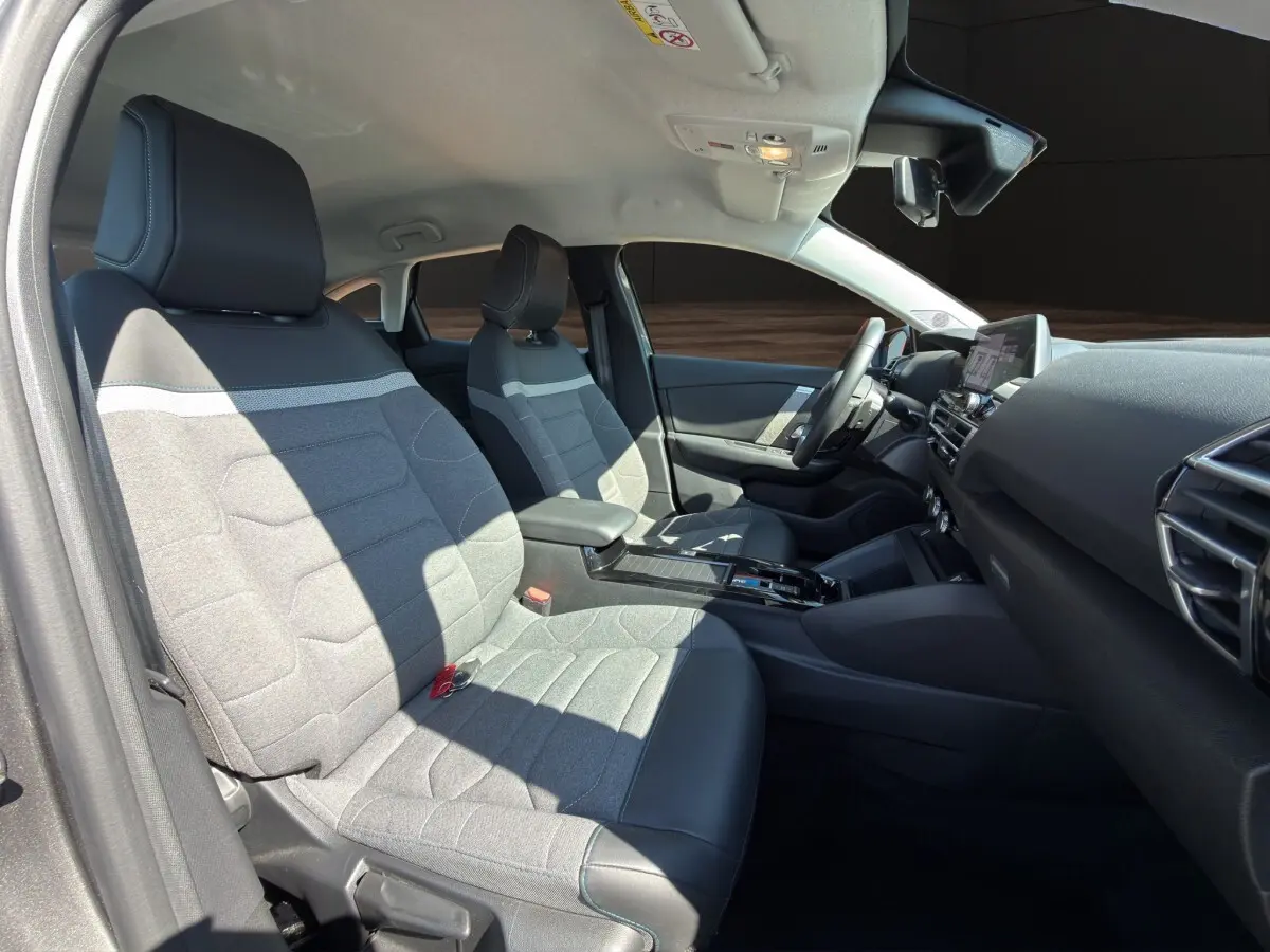 Vue intérieure côté gauche de la Citroën C4 2023, sièges tissu gris et cuir noir, tableau de bord moderne avec écran tactile.