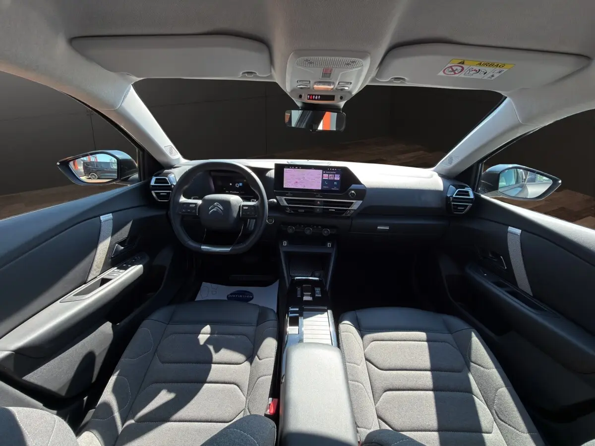 Vue intérieure avant de la Citroën C4 2023 gris foncé, volant cuir multifonctions et écran tactile central visible.