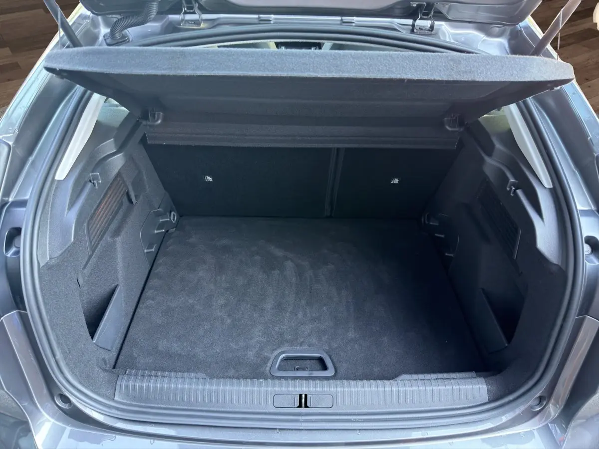 Coffre ouvert vu de l'arrière d'une Citroën C4 gris foncé 2023, espace de chargement propre et spacieux.