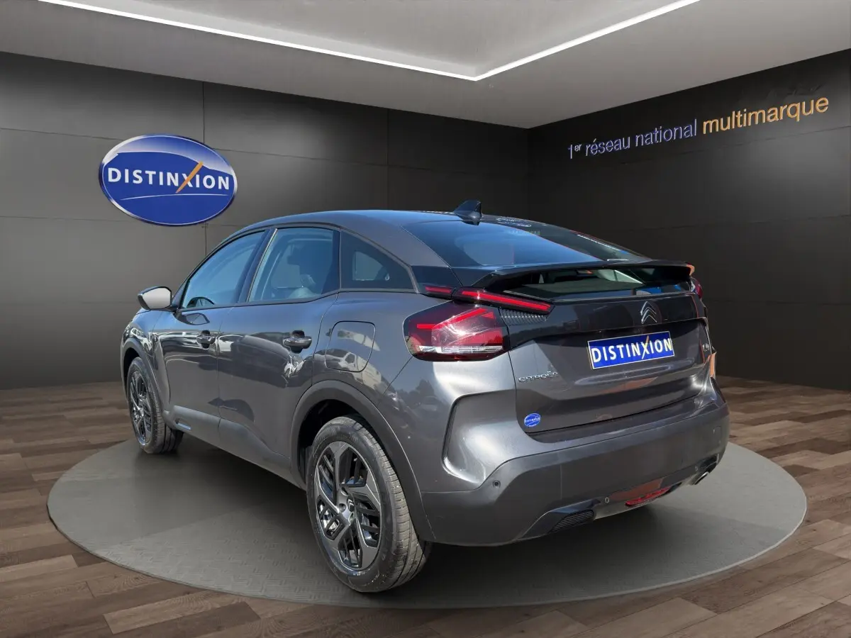 Vue 3/4 arrière droite d'une Citroën C4 gris foncé 2023 avec feux LED et jantes noires distinctives.