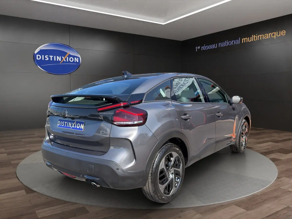 Vue 3/4 arrière droite d'une Citroën C4 gris foncé 2023 avec feux LED et spoiler de coffre visible.