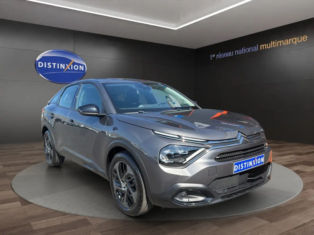 Citroën C4 gris foncé vue 3/4 avant droit, avec phares LED et calandre distinctive en showroom.