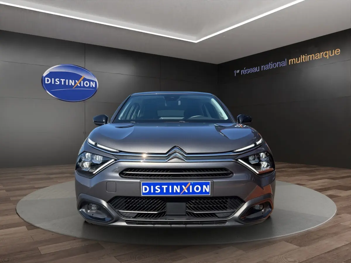 Vue frontale d'une Citroën C4 gris foncé 2023 avec phares LED et calandre distinctive en showroom.