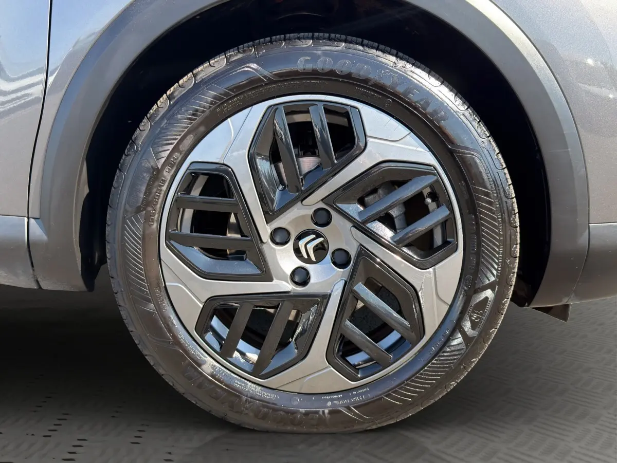 Gros plan sur la roue avant droite d'une Citroën C4 gris foncé, jante alliage au design moderne bicolore.