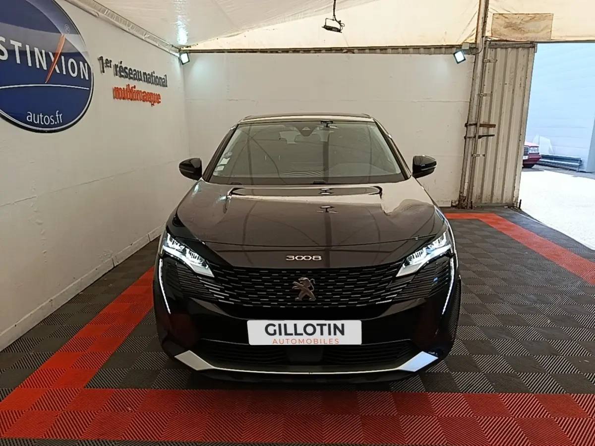 Peugeot 3008 noir vue de face dans un garage, avec calandre distinctive et feux LED allumés.