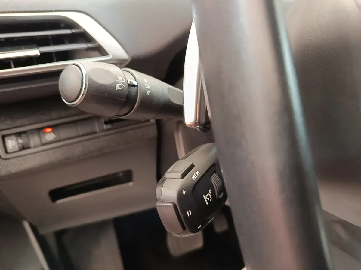 Gros plan sur la commande du régulateur de vitesse derrière le volant cuir noir du Peugeot 3008 PureTech 130 Allure.