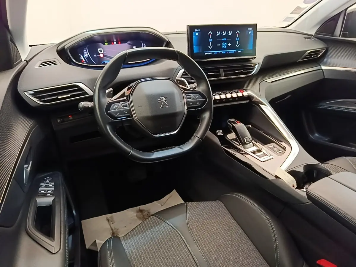Vue intérieure avant du Peugeot 3008 noir 2022, volant cuir multifonctions et écran tactile central lumineux.
