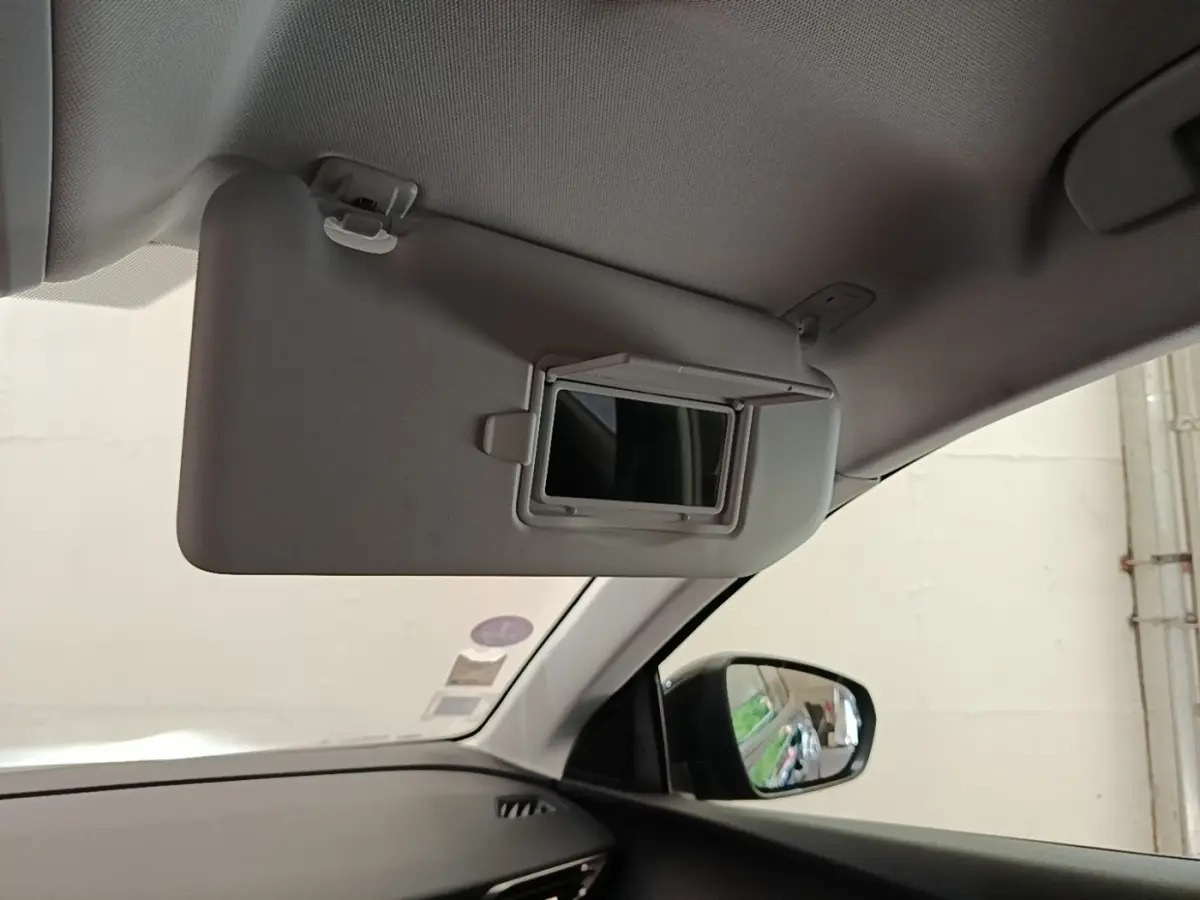 Vue intérieure côté passager du pare-soleil gris avec miroir intégré et rétroviseur extérieur noir du Peugeot 3008.