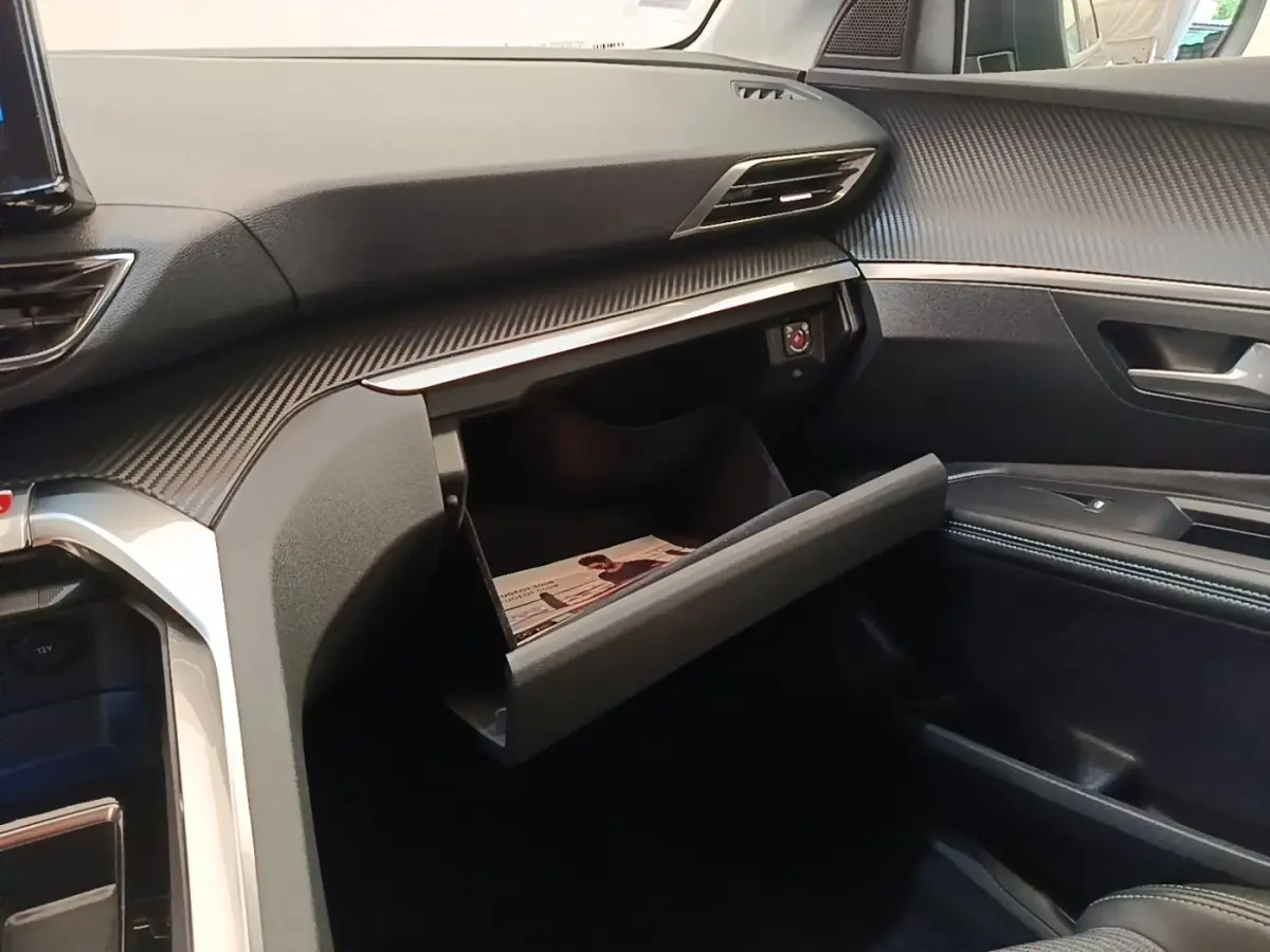 Intérieur du Peugeot 3008 PureTech 130 2022, vue côté passager sur boîte à gants ouverte et tableau de bord noir texturé.