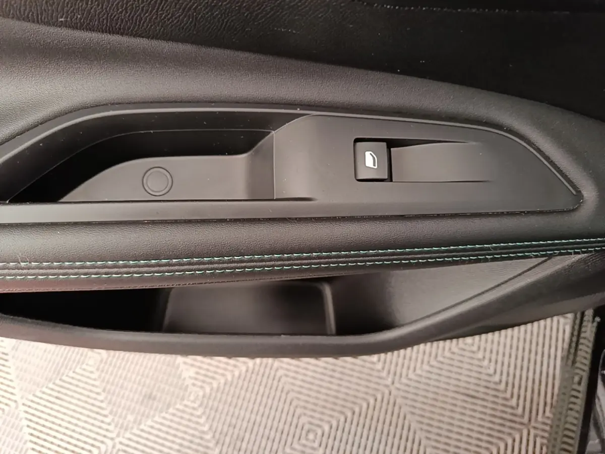 Gros plan sur la poignée intérieure côté droit de la porte d’un Peugeot 3008 noir avec couture bleue décorative.