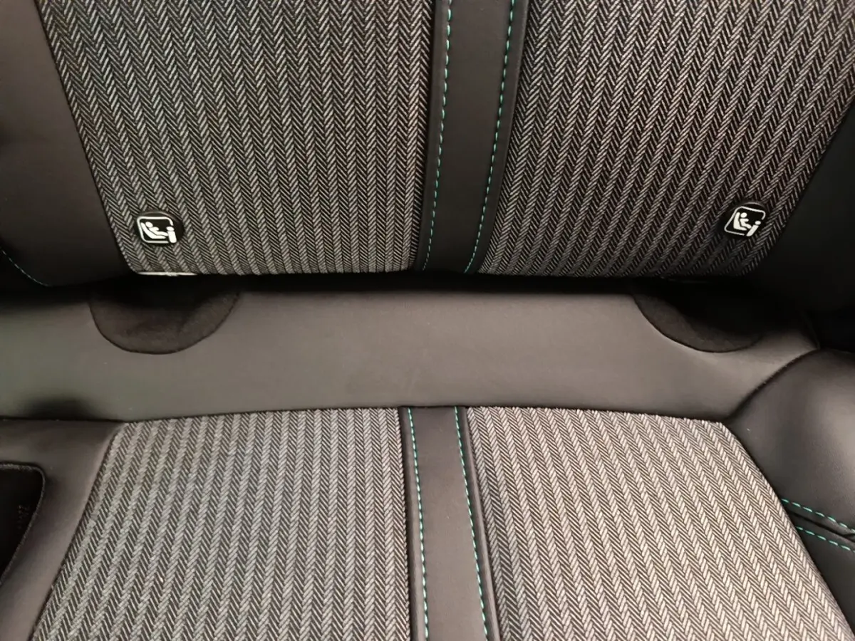 Gros plan sur la banquette arrière du Peugeot 3008 noir, tissu à motif chevrons avec surpiqûres vertes et logos Isofix.