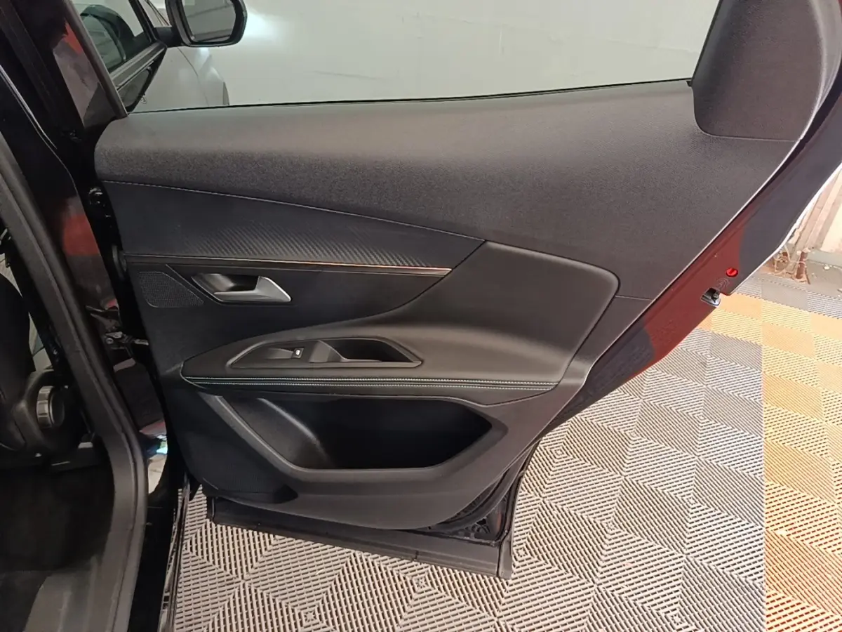 Vue intérieure de la porte arrière gauche noire du Peugeot 3008, avec garniture en tissu et insert décoratif.