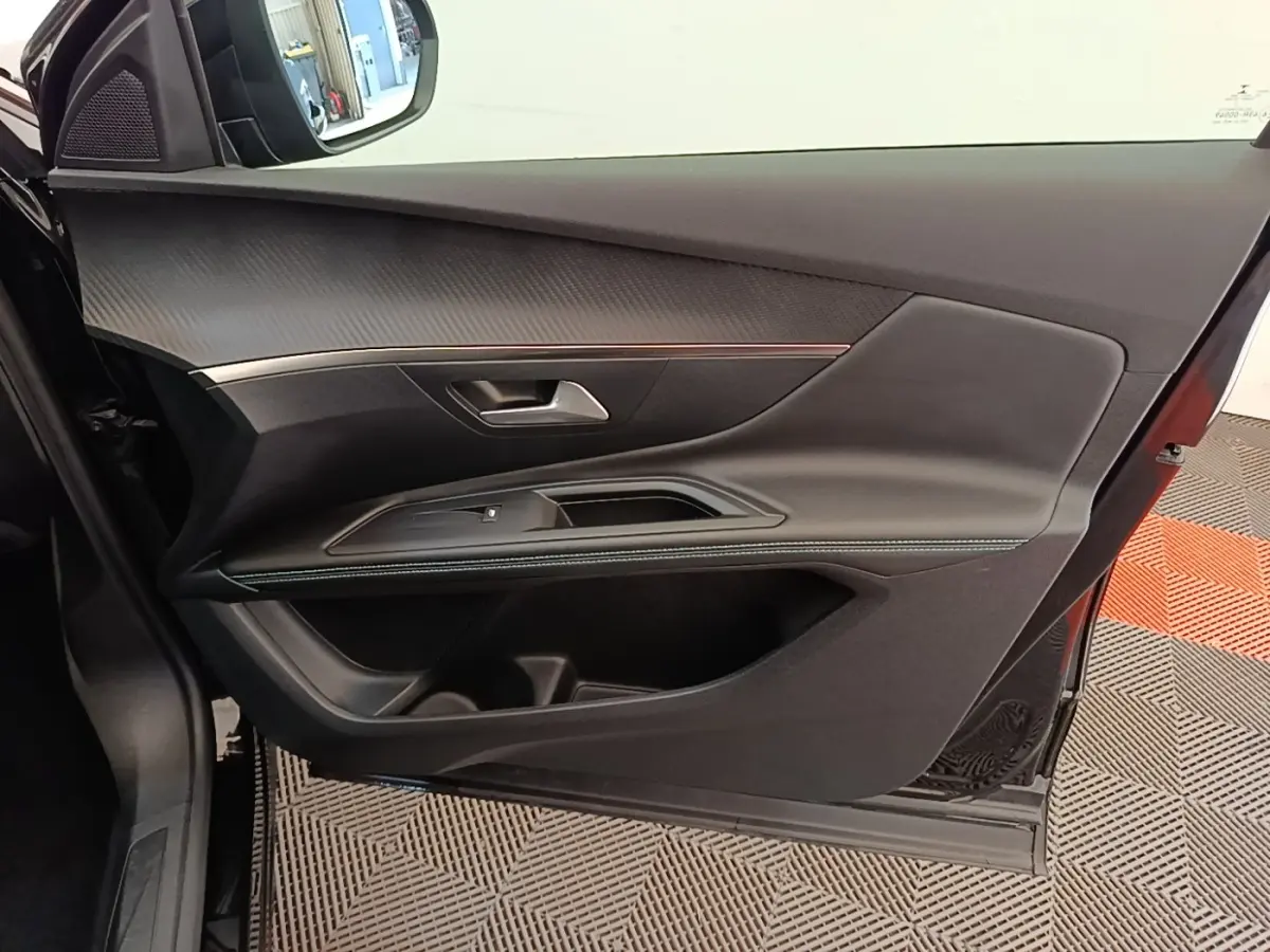 Vue intérieure de la porte avant gauche noire du Peugeot 3008 2022 avec garniture texturée et surpiqûres contrastées.