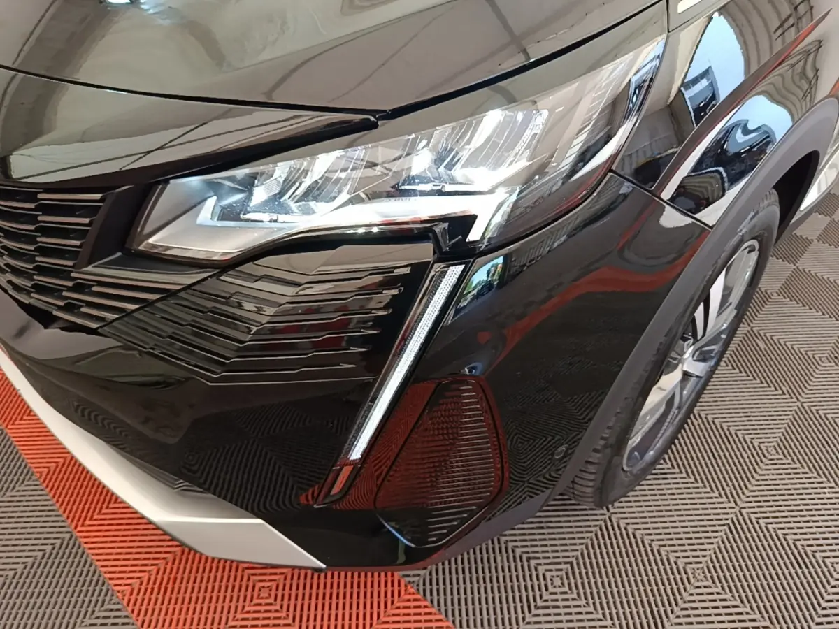 Gros plan sur l’avant droit noir brillant du Peugeot 3008 2022, mettant en valeur le phare LED et la calandre moderne.