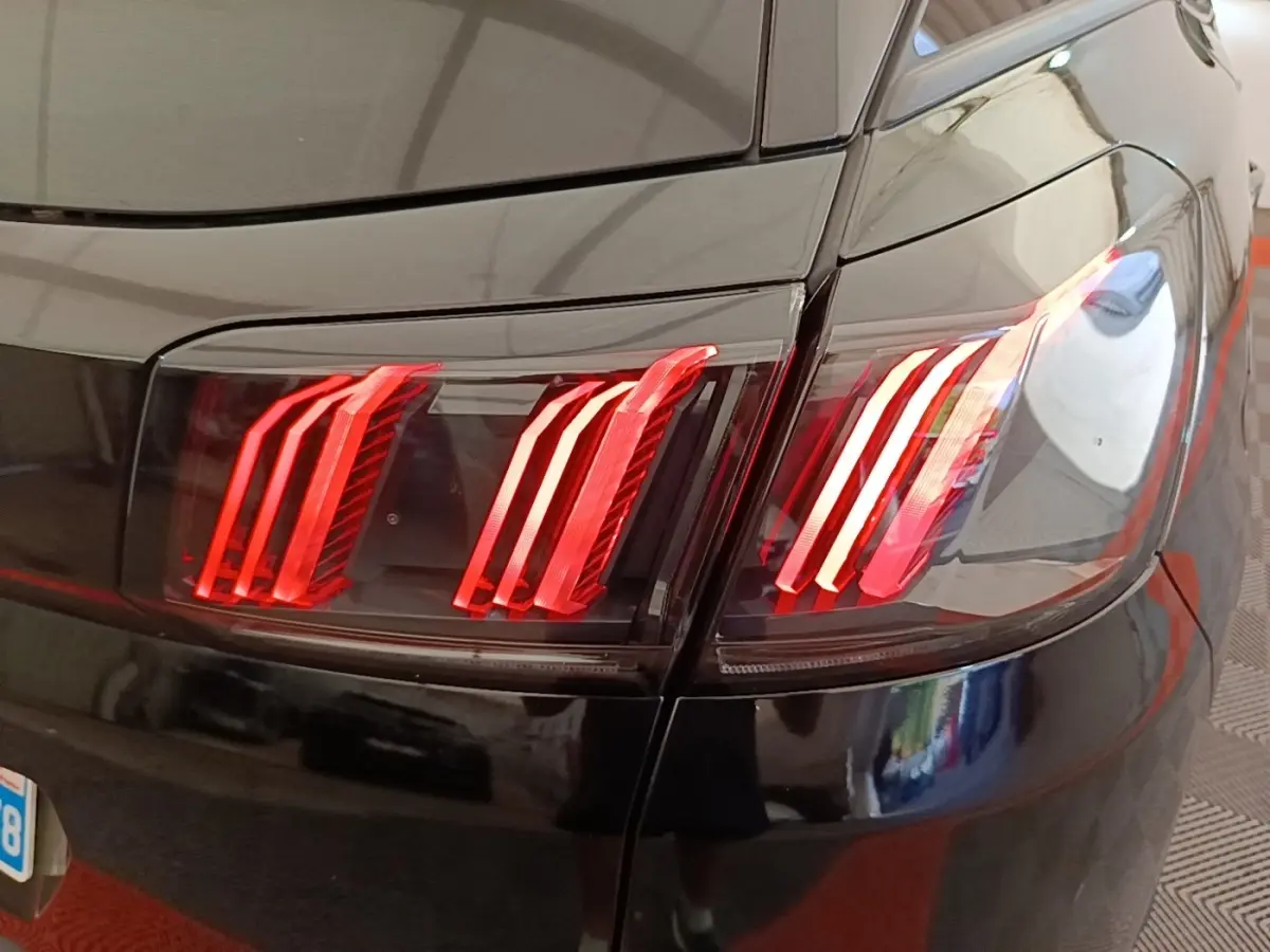 Gros plan sur les feux arrière rouges du côté gauche d’un Peugeot 3008 noir, finition Allure 2022.