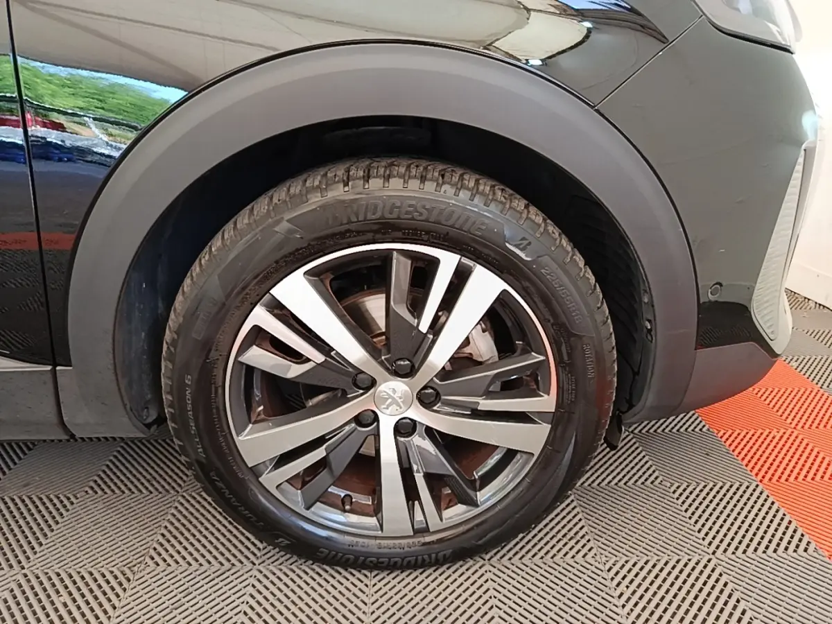 Gros plan sur la roue avant gauche noire du Peugeot 3008 avec jante alliage bicolore et pneu Bridgestone.