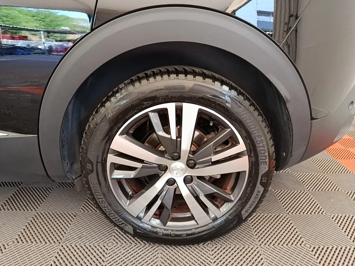 Gros plan sur la roue arrière droite d’un Peugeot 3008 noir, mettant en valeur la jante alliage moderne et le pneu Bridgestone.