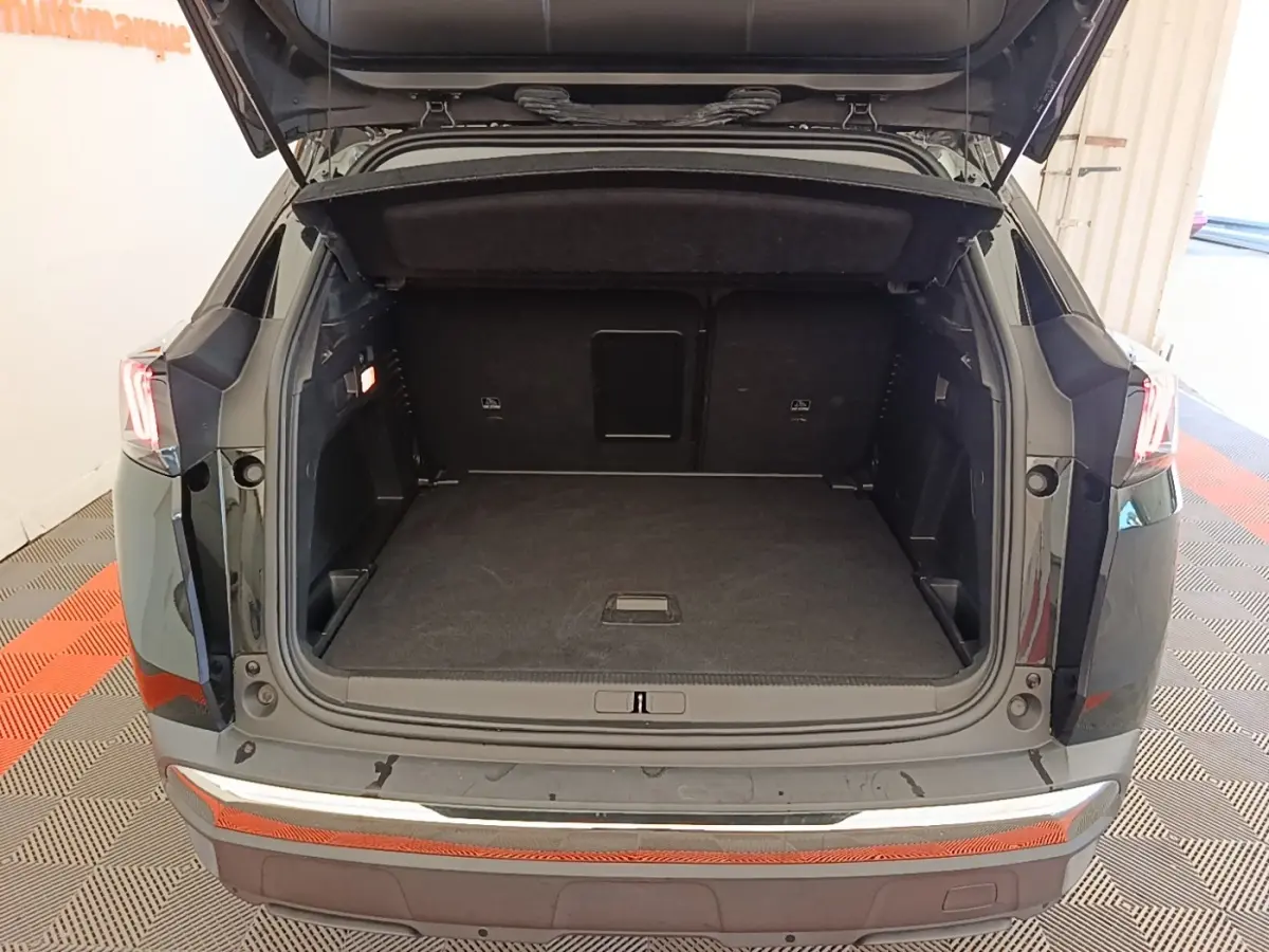 Coffre ouvert vu de l'arrière d'un Peugeot 3008 noir, montrant un espace de chargement spacieux et propre.