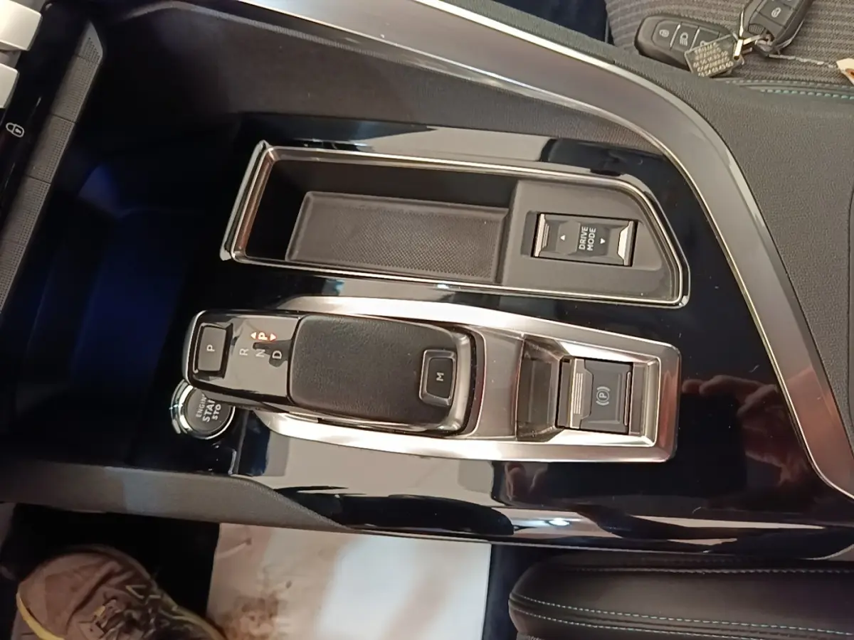 Vue rapprochée de la console centrale noire brillante du Peugeot 3008 avec levier de vitesse automatique et boutons multifonctions.