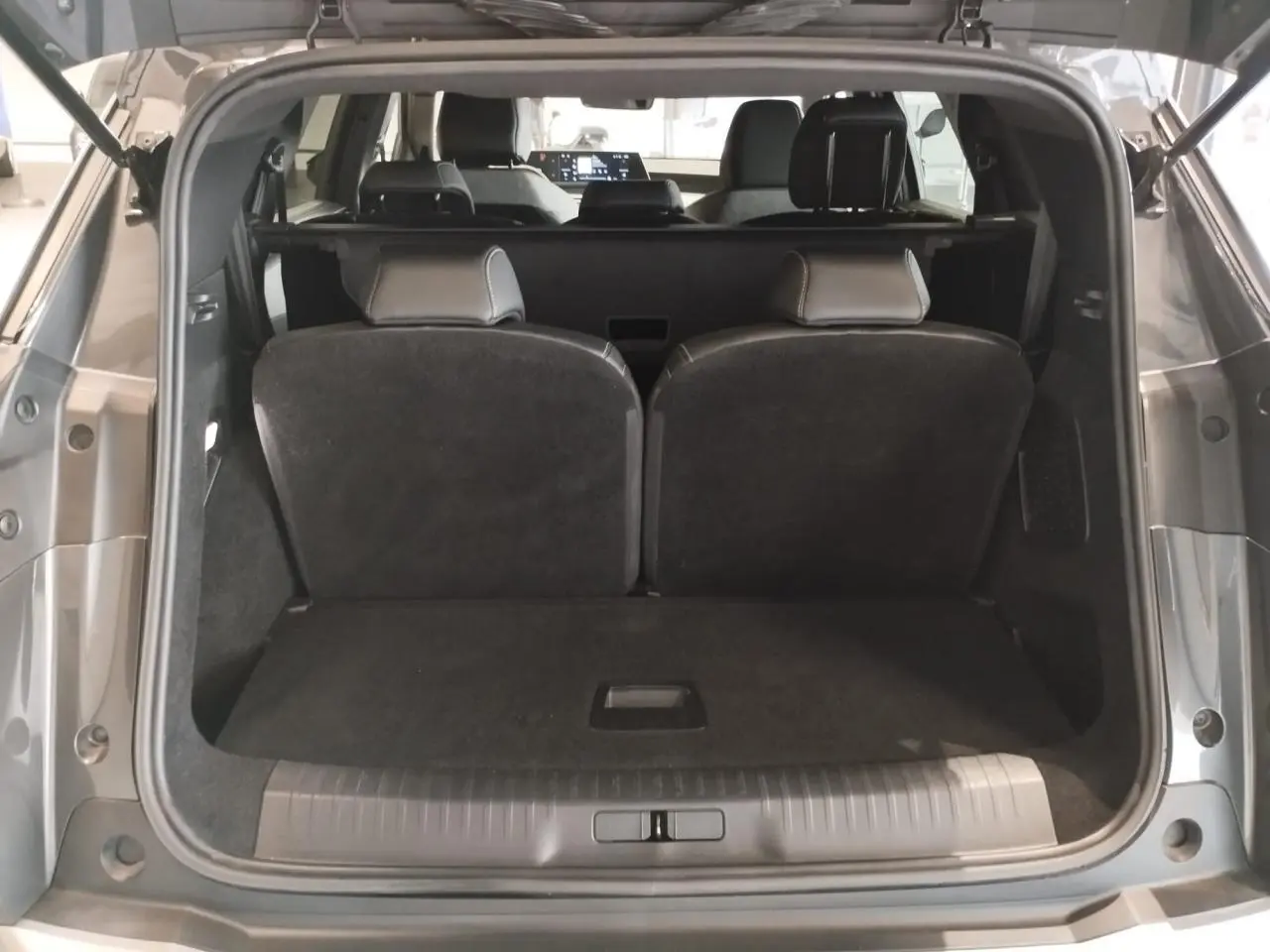 Coffre ouvert d’un Peugeot 5008 gris titanium, vue arrière montrant la banquette rabattue et l’habitacle intérieur.