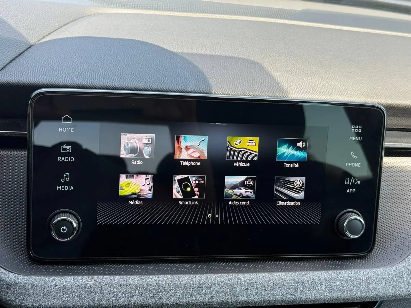 Écran tactile central du Skoda Kamiq 2025 affichant les menus radio, téléphone, véhicule et climatisation, avec finition intérieure grise.