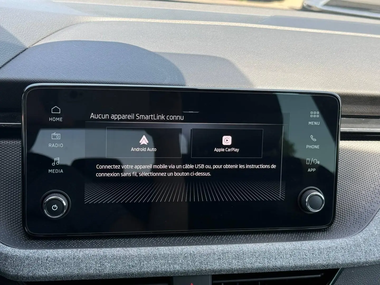 Écran tactile central du Skoda Kamiq 2025 affichant les options Android Auto et Apple CarPlay, entouré d'un tableau de bord gris.