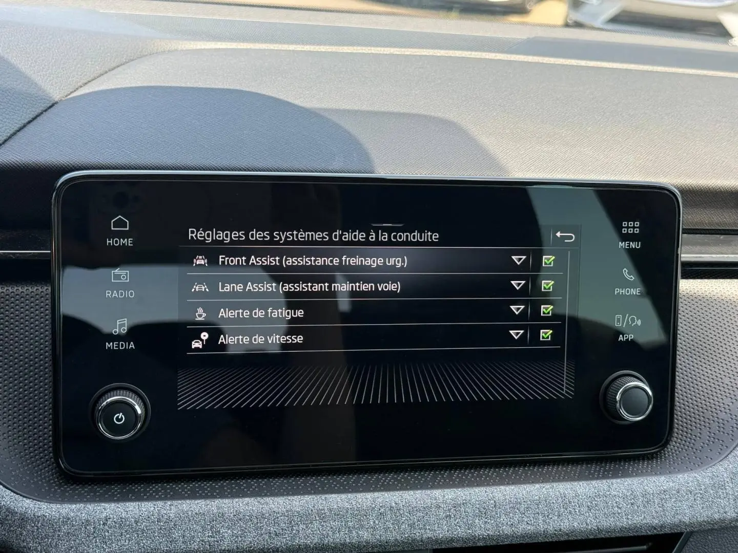 Écran tactile central du Skoda Kamiq 2025 affichant les réglages des aides à la conduite, intérieur gris et noir.