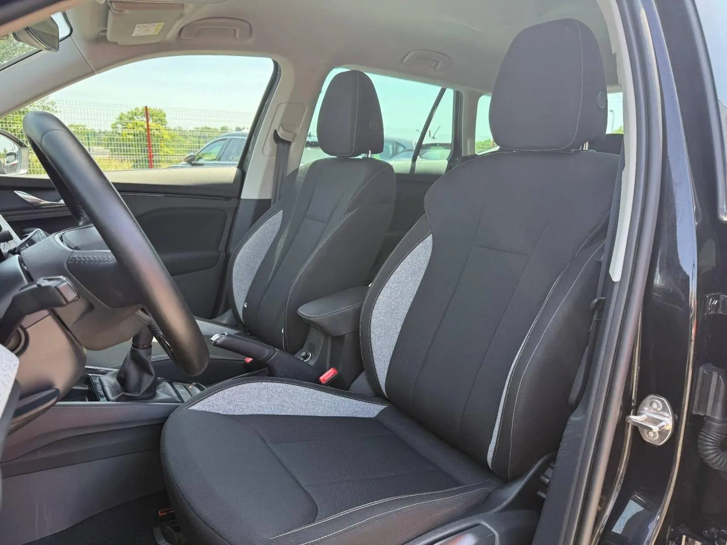 Vue intérieure côté conducteur du Skoda Kamiq 2025 noir Magic nacré, sièges tissu bicolore avec surpiqûres blanches.