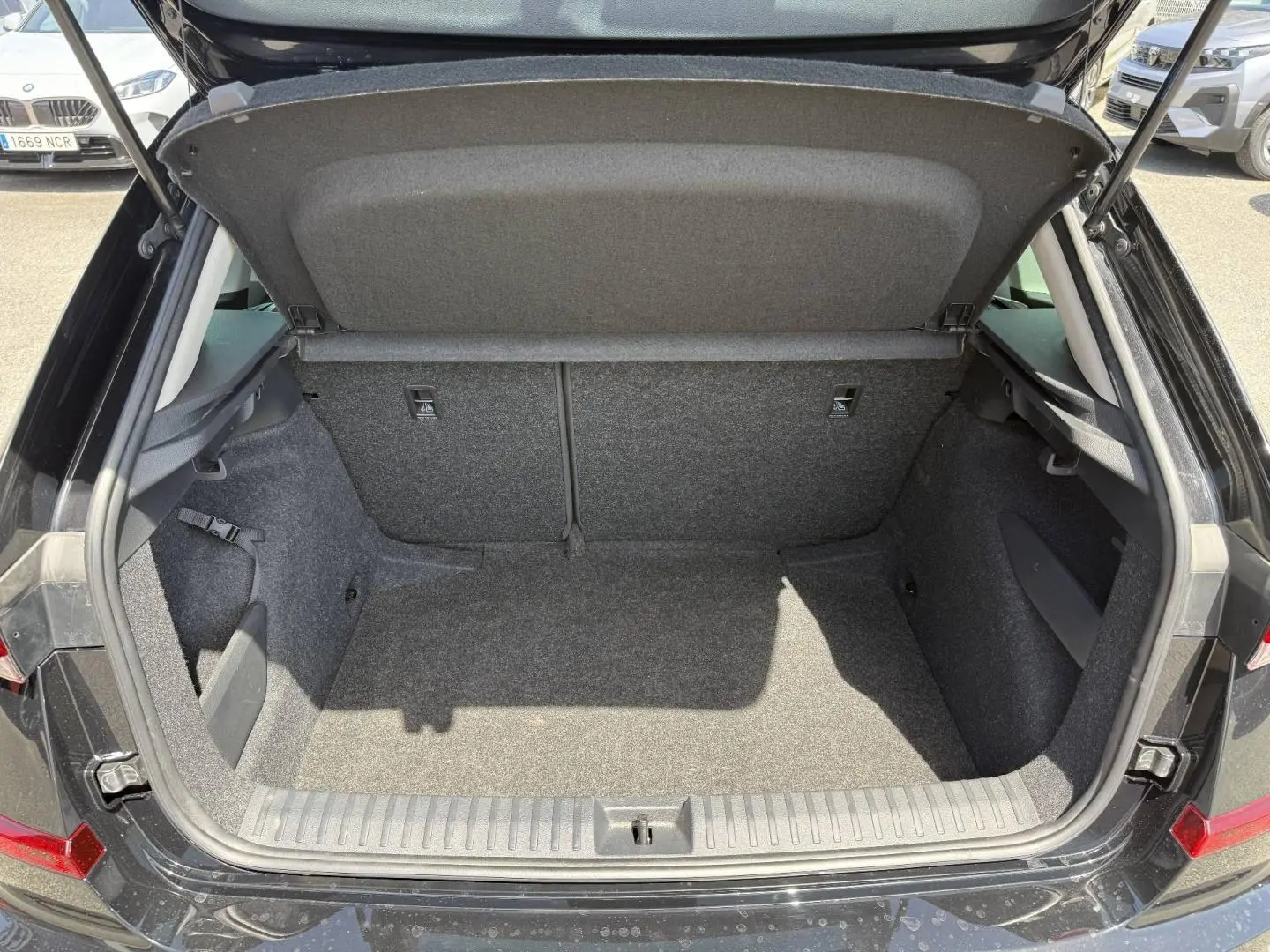 Coffre ouvert vu de l'arrière d'un Skoda Kamiq 2025 noir Magic nacré, montrant un espace de chargement vide et propre.