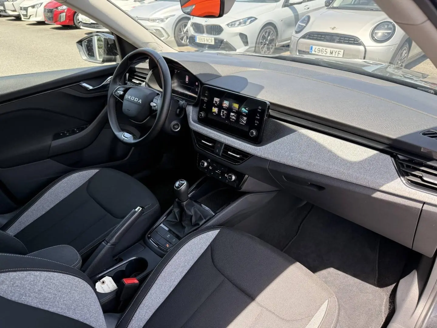 Vue intérieure côté conducteur du Skoda Kamiq 2025, avec tableau de bord moderne et sellerie bicolore noire et grise.