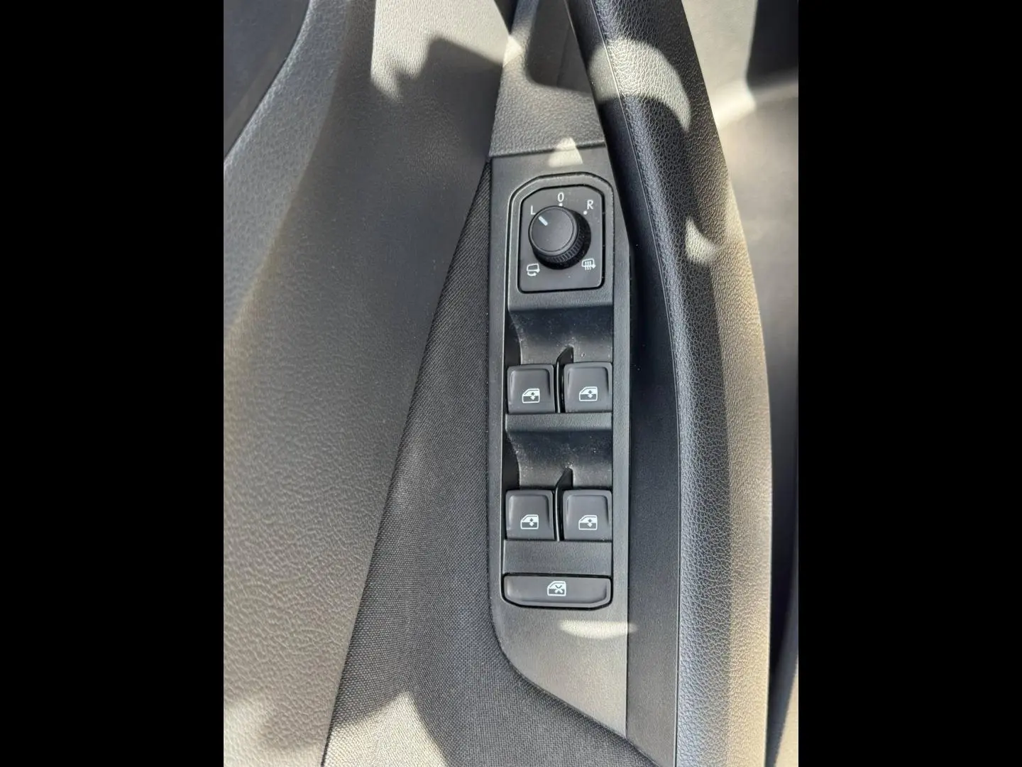 Vue rapprochée des commandes de lève-vitres et réglage des rétroviseurs côté conducteur du Skoda Kamiq 2025 noir Magic nacré.