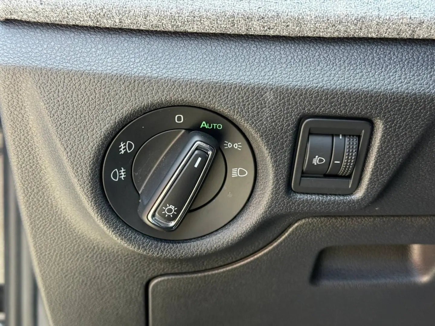 Gros plan sur la commande d’éclairage intérieur du Skoda Kamiq 2025 en Noir Magic nacré, avec réglage automatique des phares.
