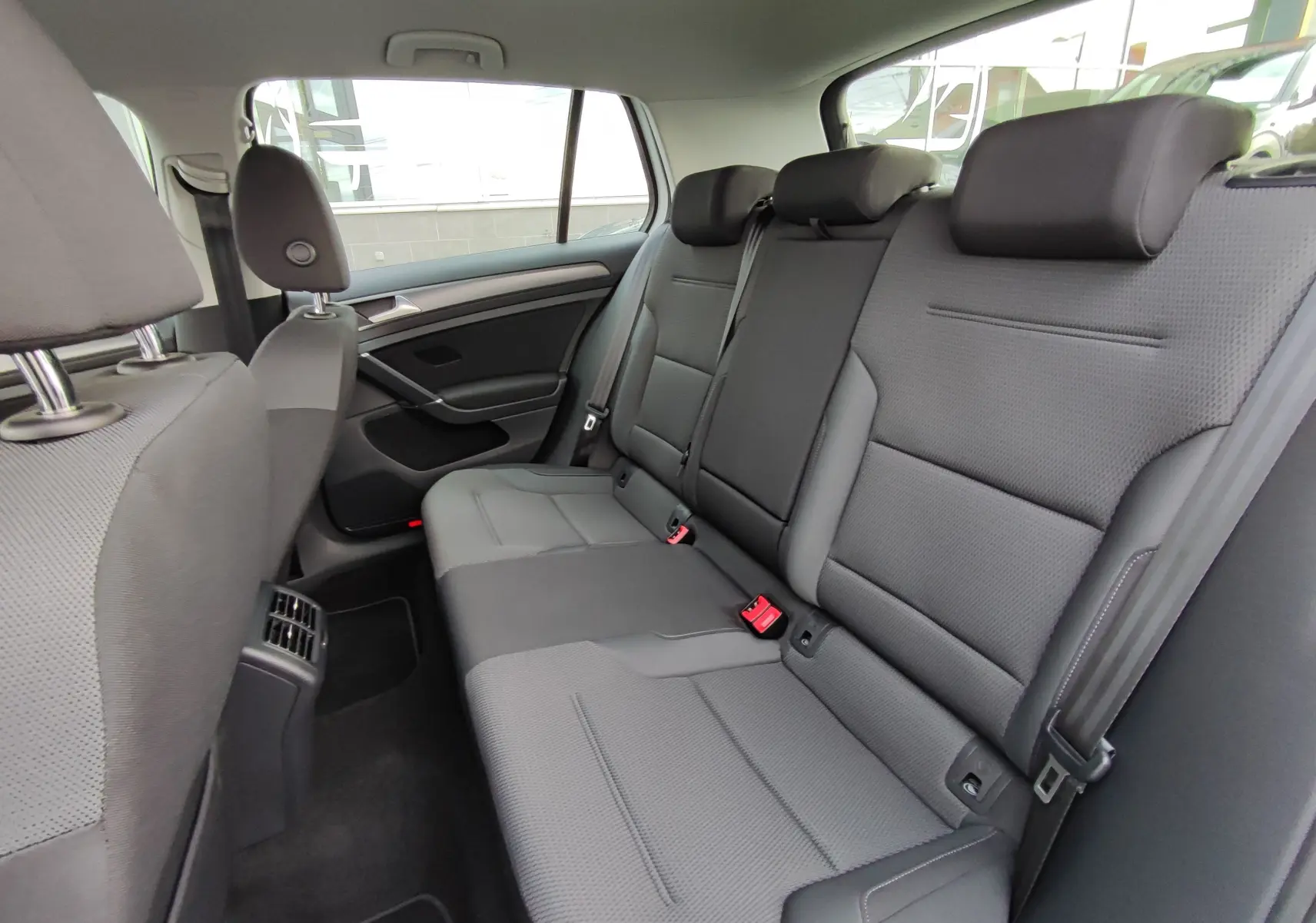 Vue intérieure côté droit des sièges arrière gris foncé d'une Volkswagen Golf 1.5 TSI EVO 2019, avec appuie-têtes et ceintures visibles.
