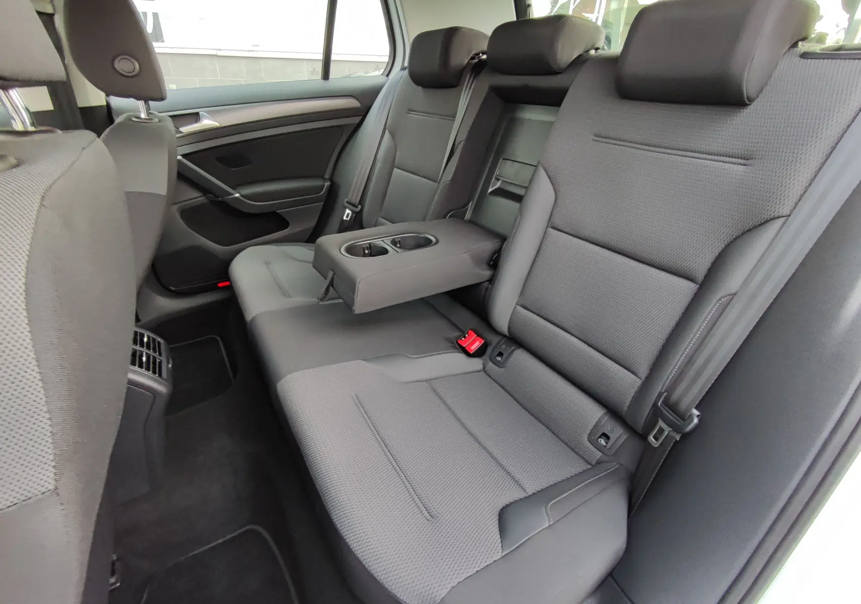 Vue intérieure côté droit des sièges arrière gris foncé de la Volkswagen Golf 1.5 TSI EVO 2019 avec accoudoir central relevé.