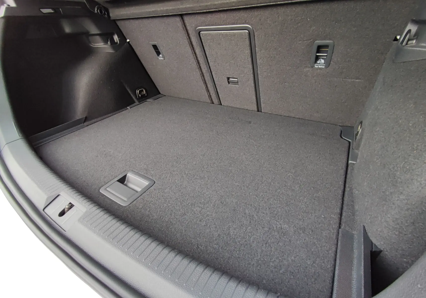 Coffre spacieux de Volkswagen Golf 1.5 TSI EVO blanc, vue intérieure en plongée montrant le plancher et les fixations.